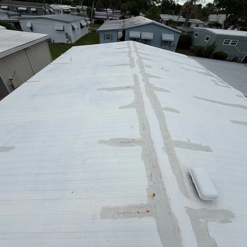 White metal mobile home roof in Leesburg, FL covered in old sealant patches along the seams, before roof coating