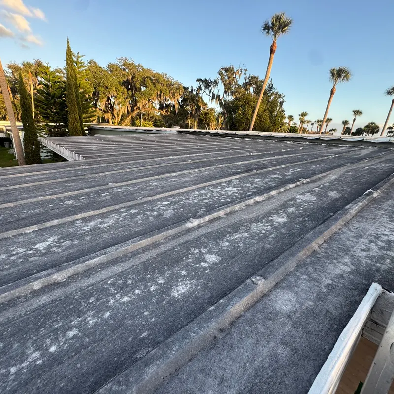 Weathered, stained aluminum pan roof over a sunroom in Lake County, FL before replacement